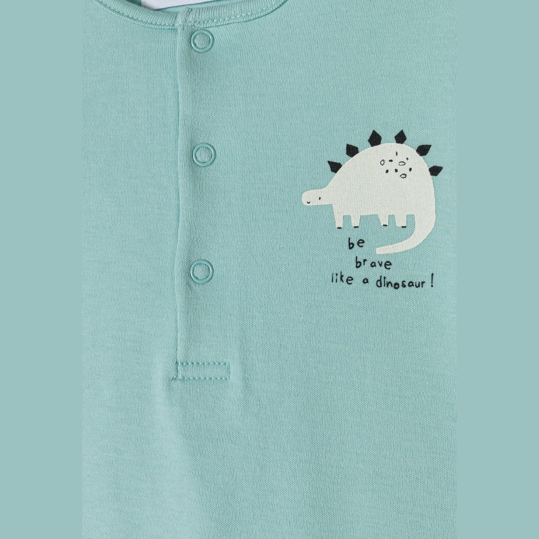 Detail of mint green romper showing snap button placket and white dinosaur applique with text 'be brave like a dinosaur!' on chest area