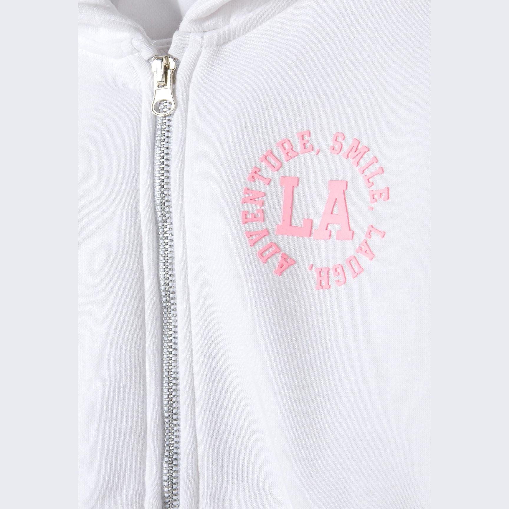 Close-up detail of white shorts showing pink circular L.A. logo with 'SMILE' text around the border