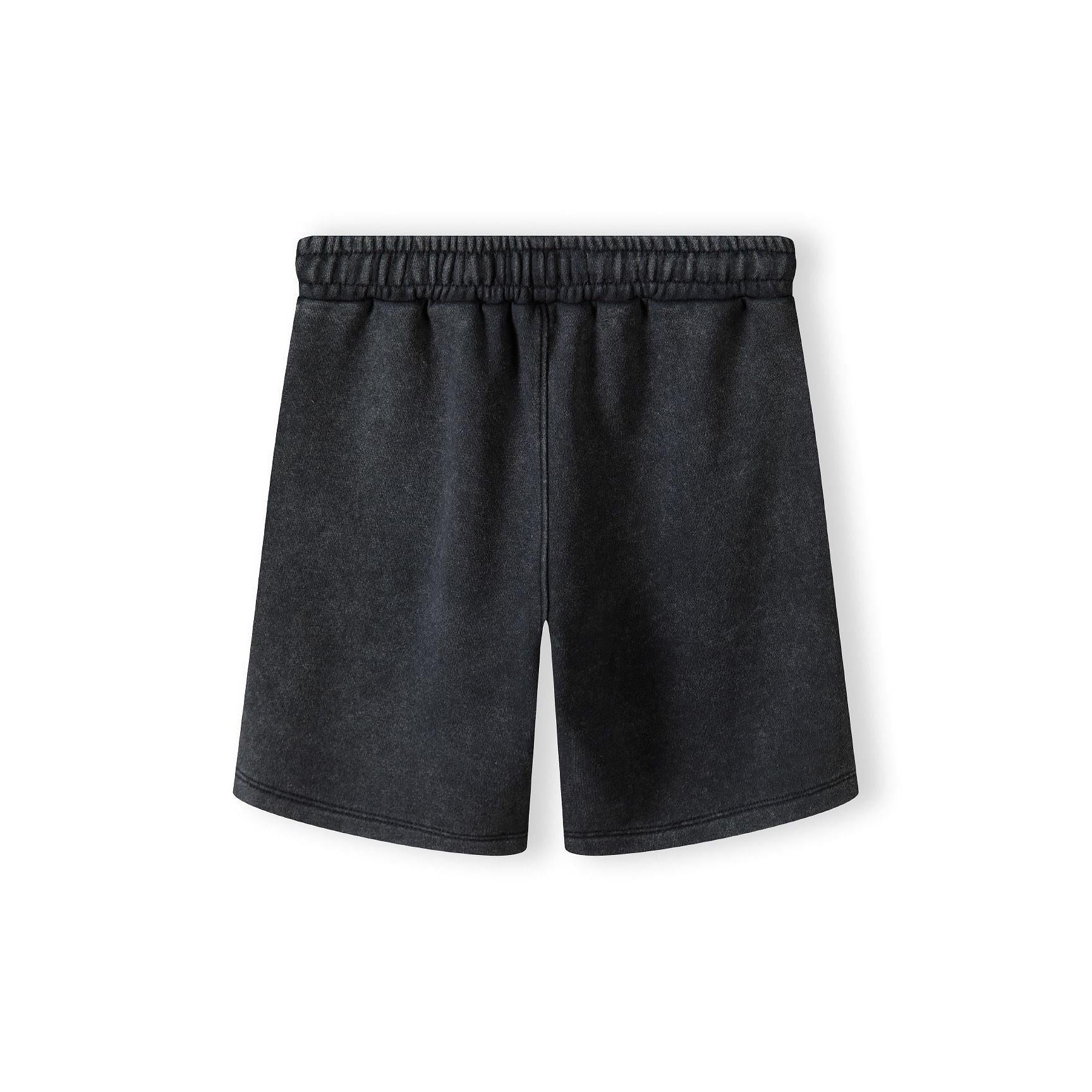 Close-up detail of washed grey fleece shorts showing elasticated waistband with white label and soft fabric texture