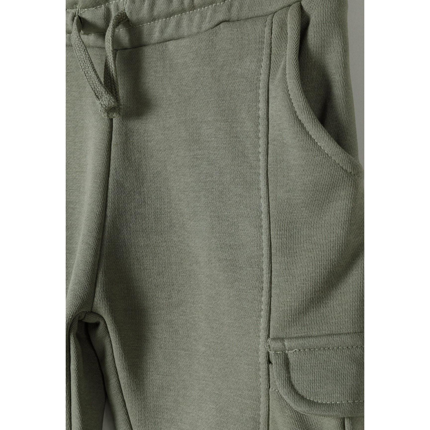 Close-up detail of khaki cargo joggers showing side cargo pocket with flap closure and fabric texture
