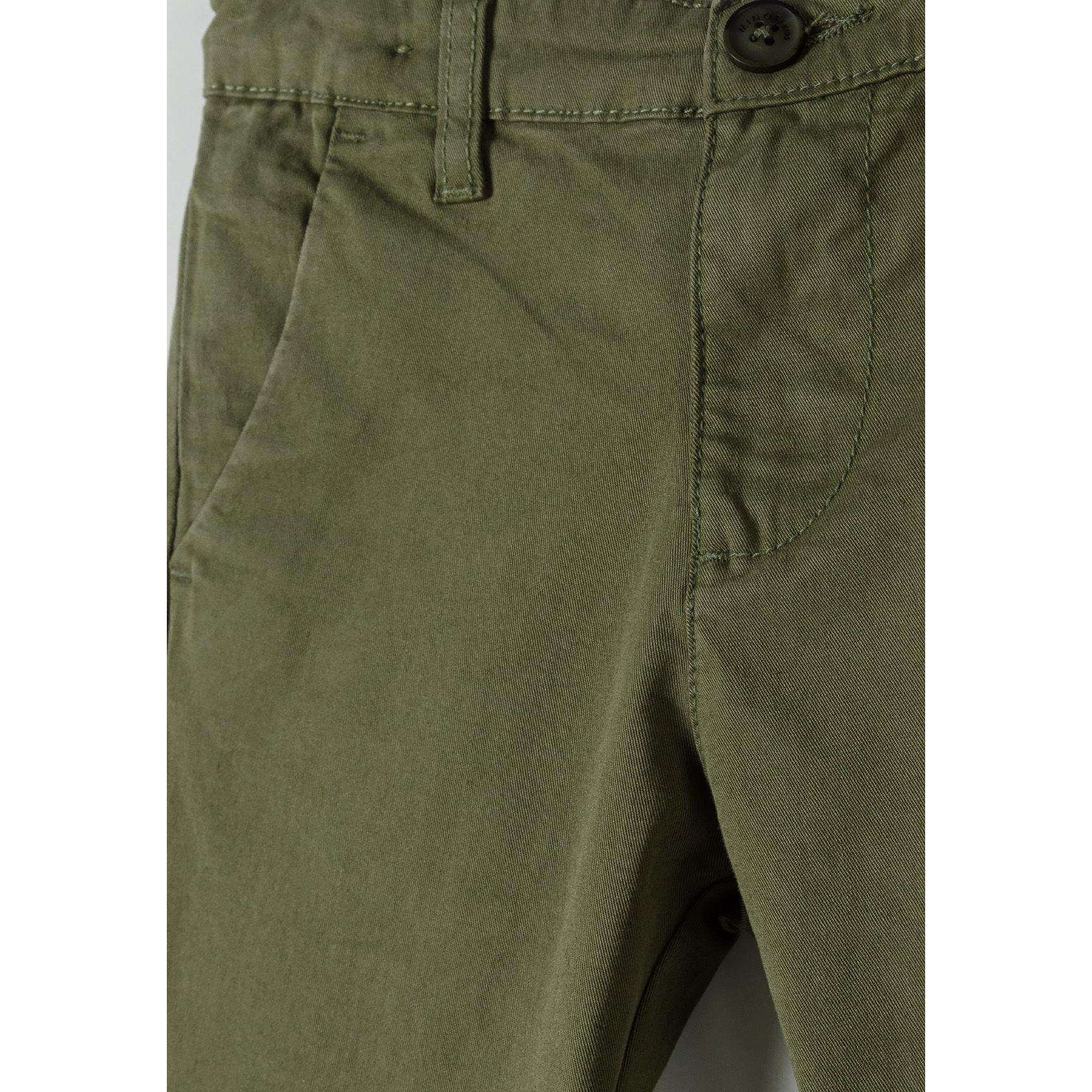 Close-up detail of olive chino trouser waistband showing button closure and front pocket construction