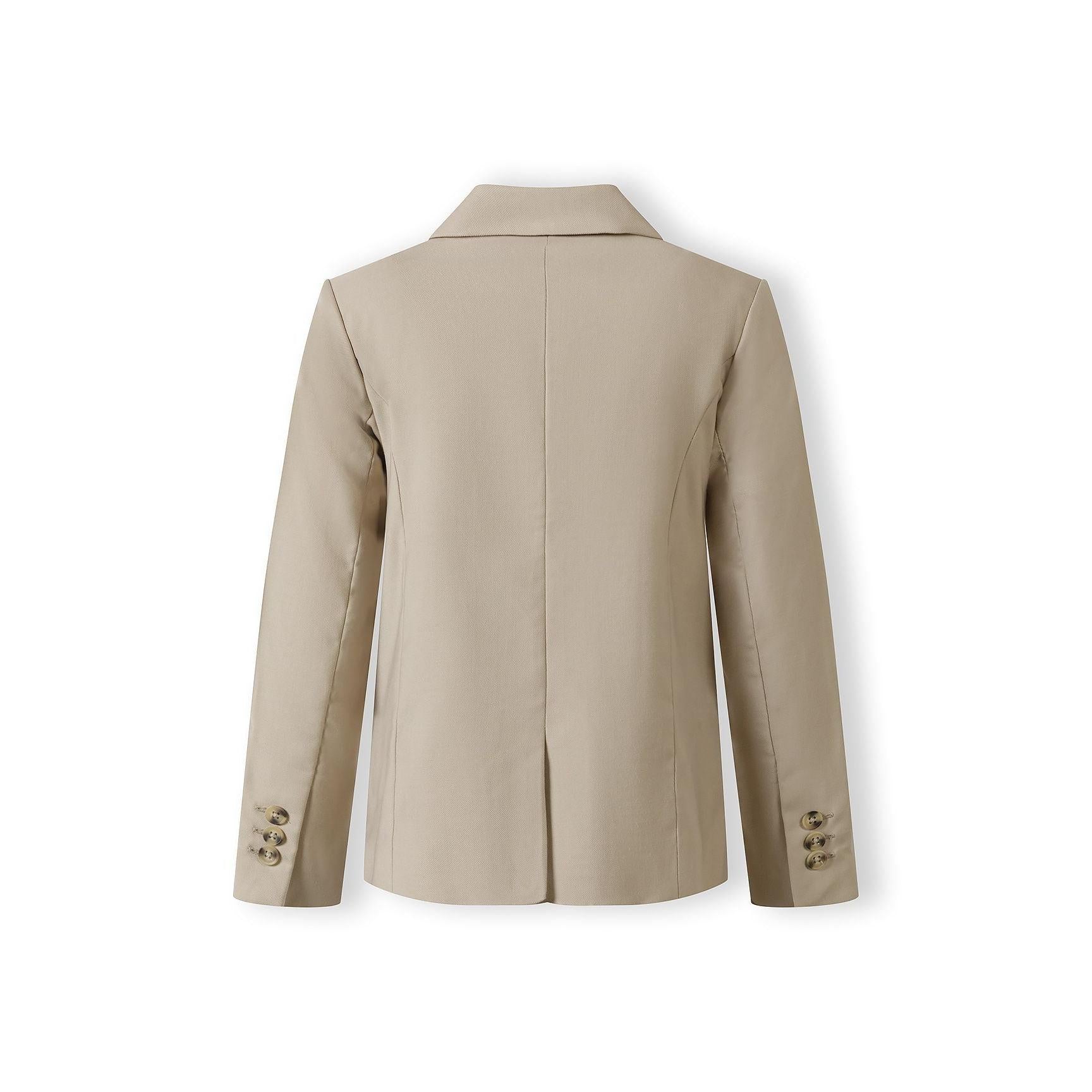 Full length view of boy in complete stone suit pointing at camera, wearing white trainers against grey studio background