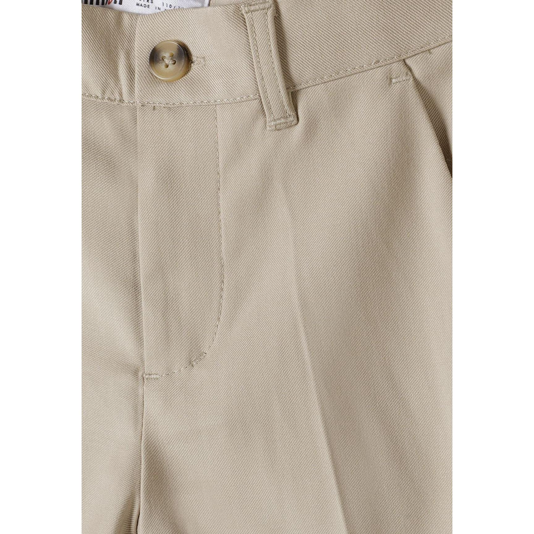 Young boy in complete stone suit pointing forward playfully, wearing white sneakers against light background