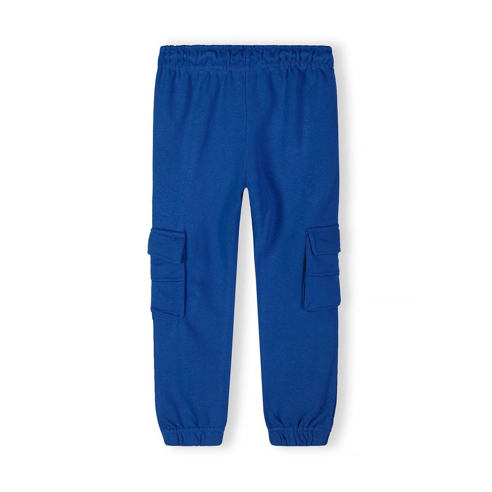 Close-up detail of royal blue t-shirt showing ribbed crew neckline and black rectangular Minoti logo patch with white text