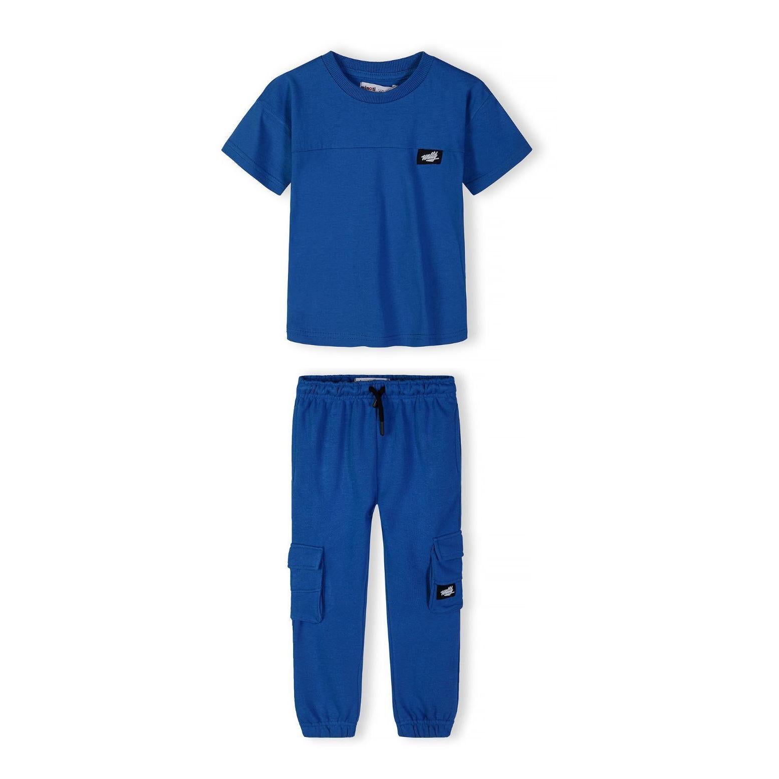 Close-up detail of royal blue t-shirt showing ribbed crew neckline and black rectangular Minoti logo patch with white text