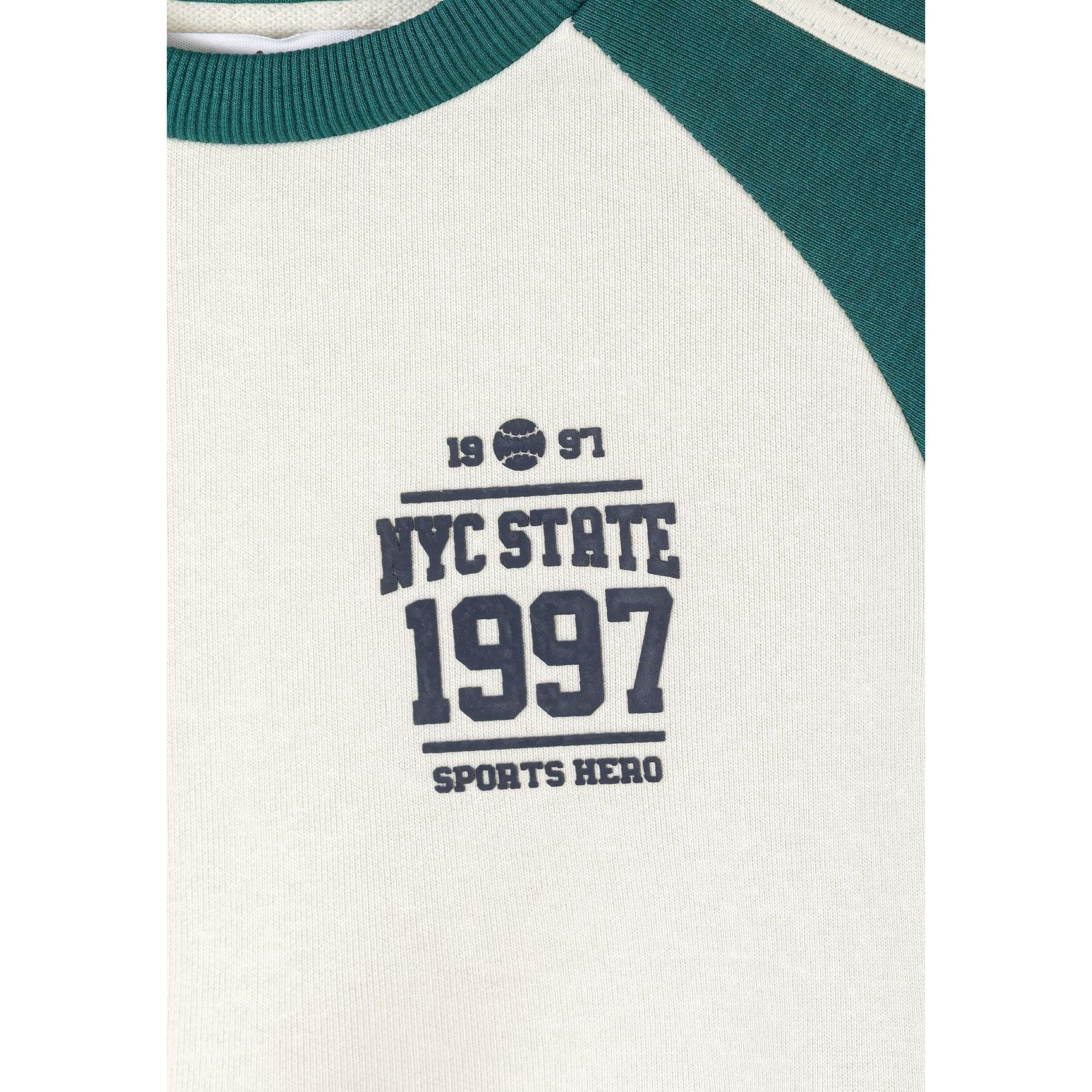 Close-up detail of sweatshirt chest area showing NYC State 1997 Sports Hero print in navy lettering on cream fabric with green neckline