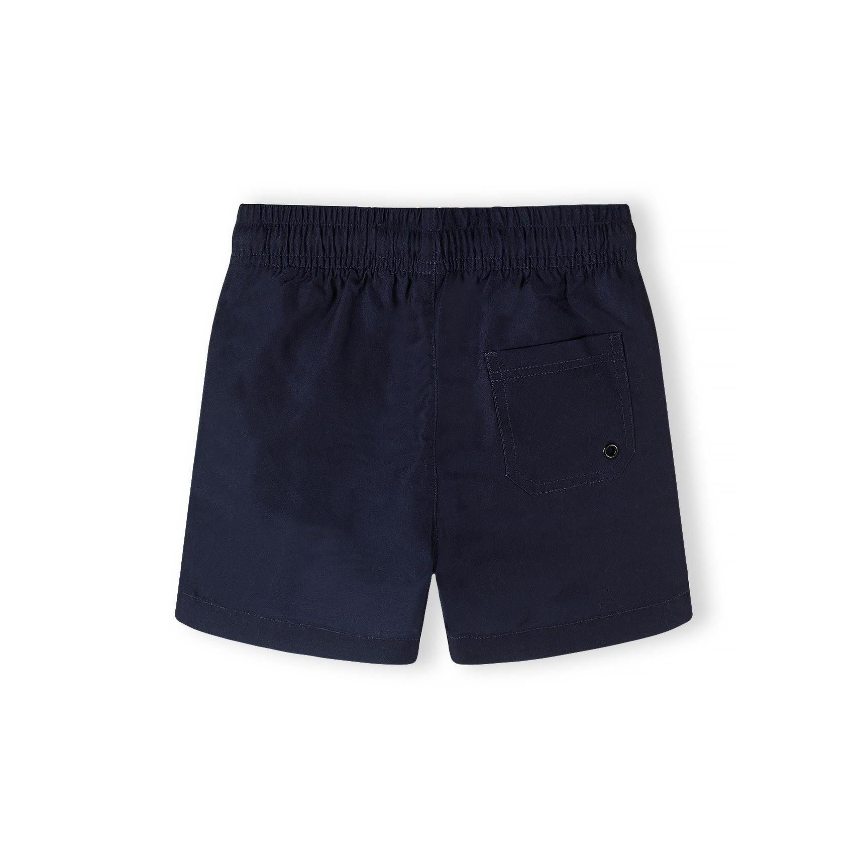 Close-up detail of navy swim shorts showing drawstring ties, elastic waistband and orange logo embroidery