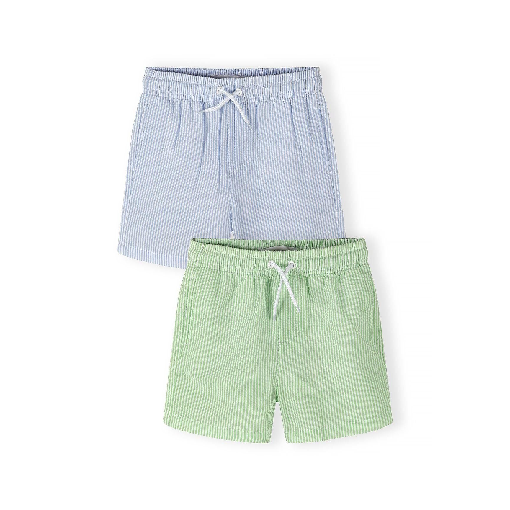 Two pairs of striped swim shorts - light blue and mint green with white vertical stripes, elasticated waistband with white drawstring, laid flat on white background