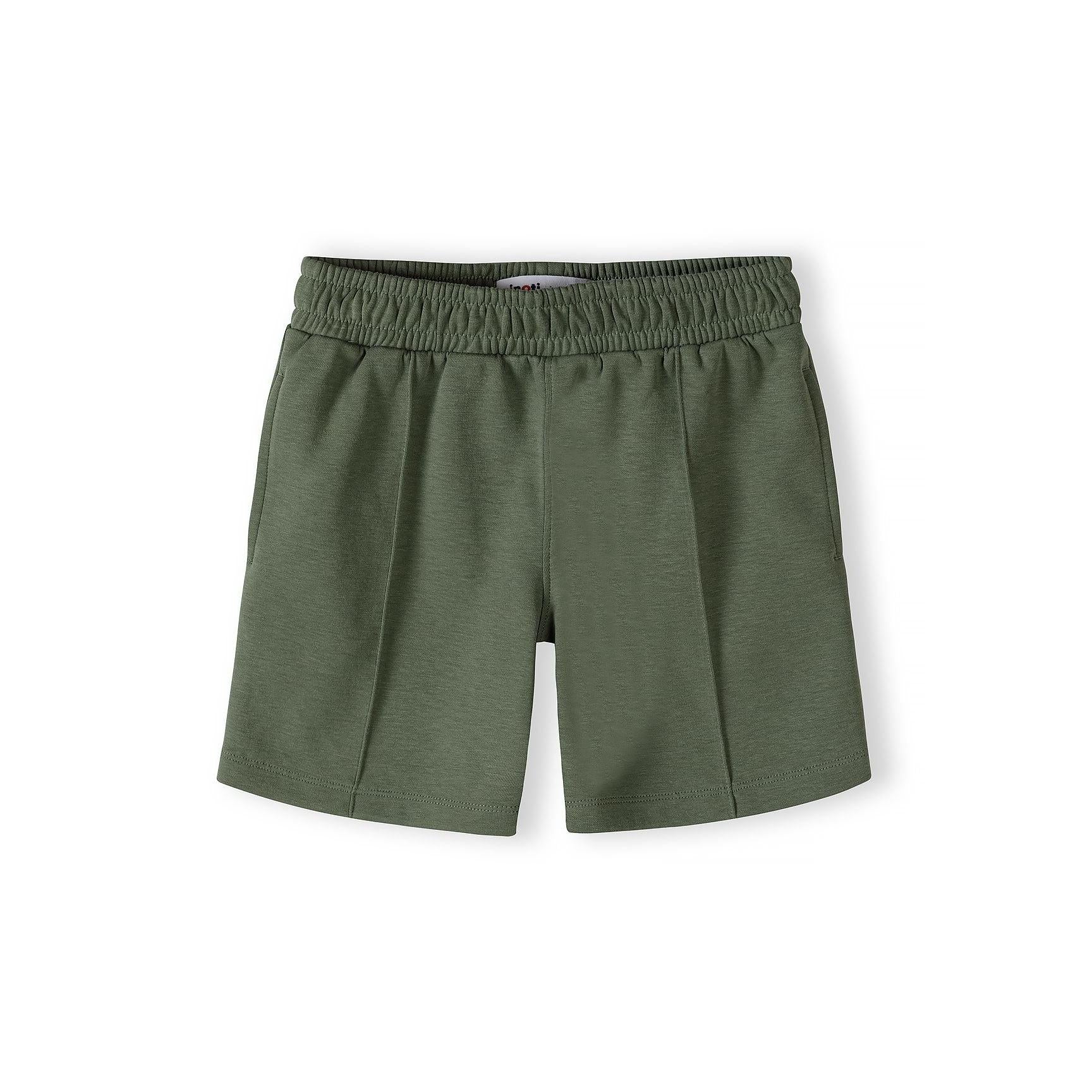 Close-up detail of teal polo shirt showing Minoti label, half-zip closure, contrast collar trim and embroidered star logo