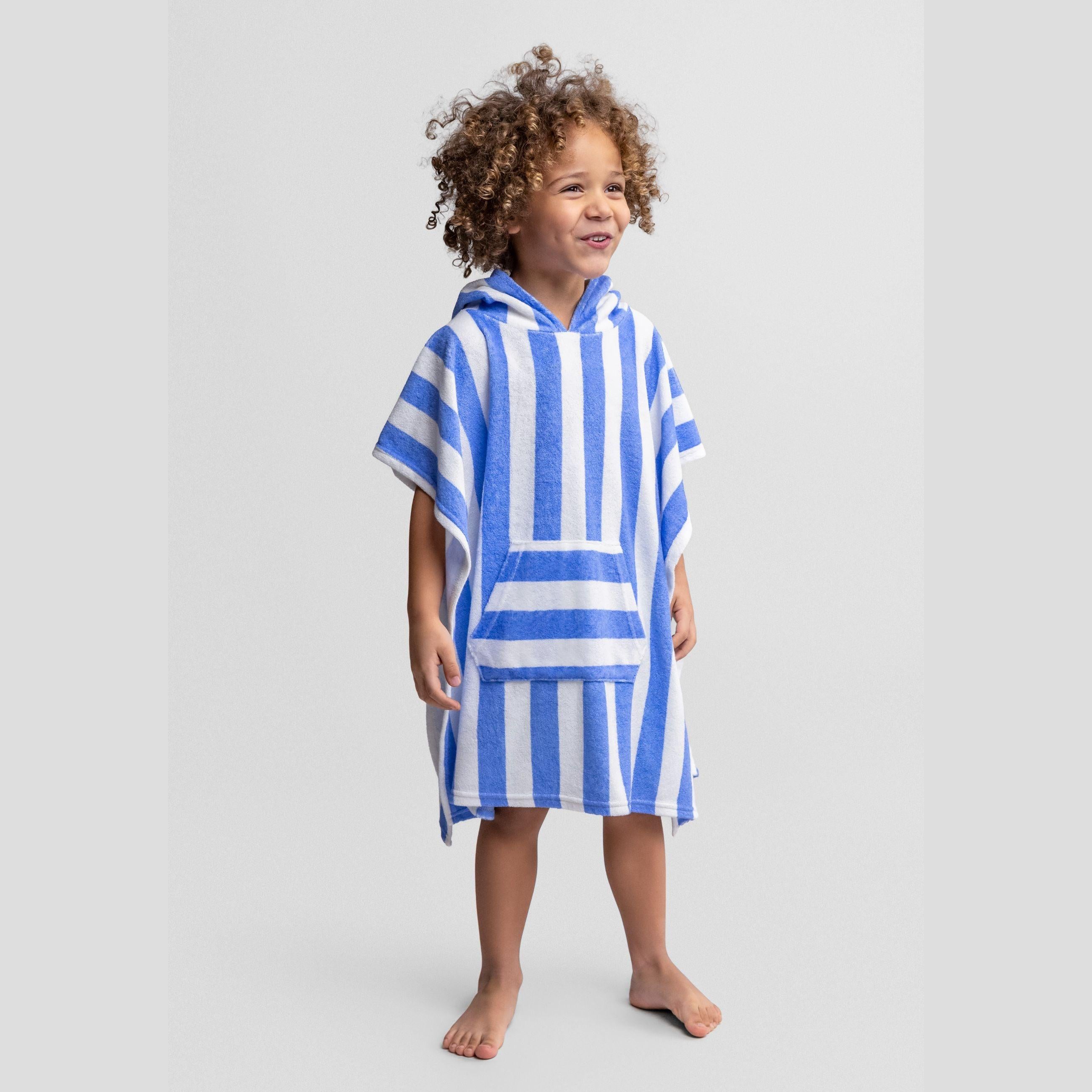 Child wearing blue and white striped hooded towelling cover-up poncho with relaxed fit, standing against white background