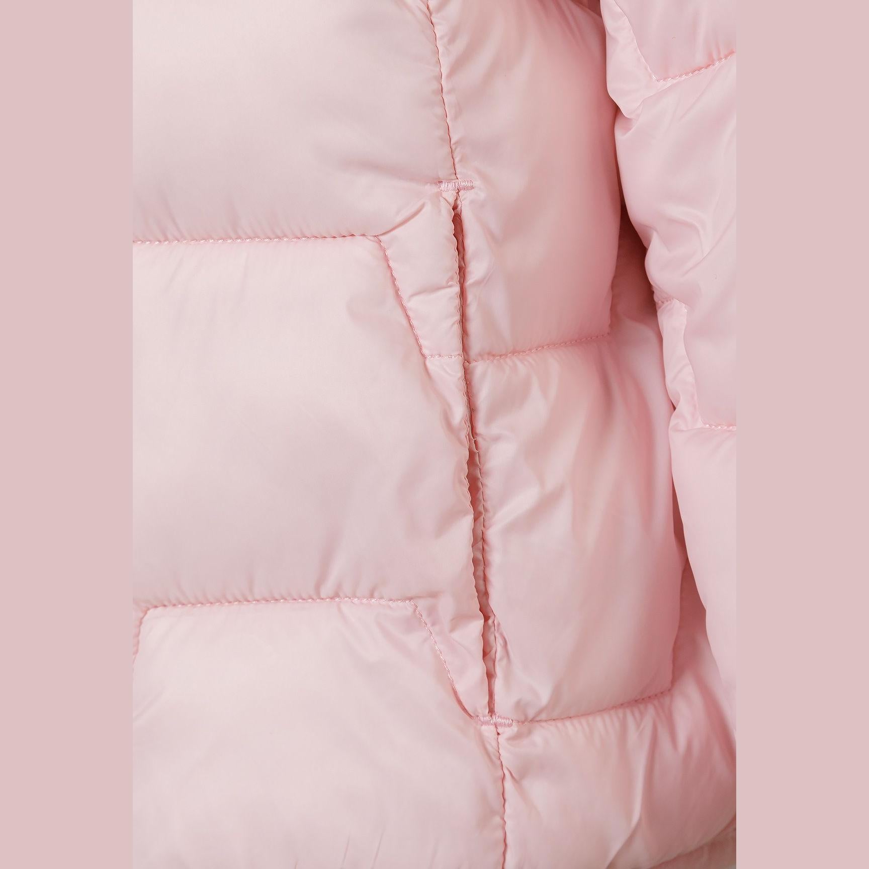 Close-up detail shot of pink quilted jacket showing padded texture, seam construction and soft pink tonal background