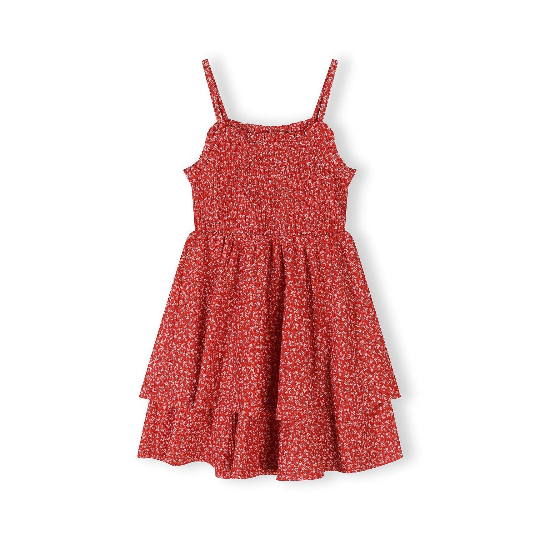 Flat lay of red floral sleeveless dress showing shirred bodice construction and adjustable straps against white background