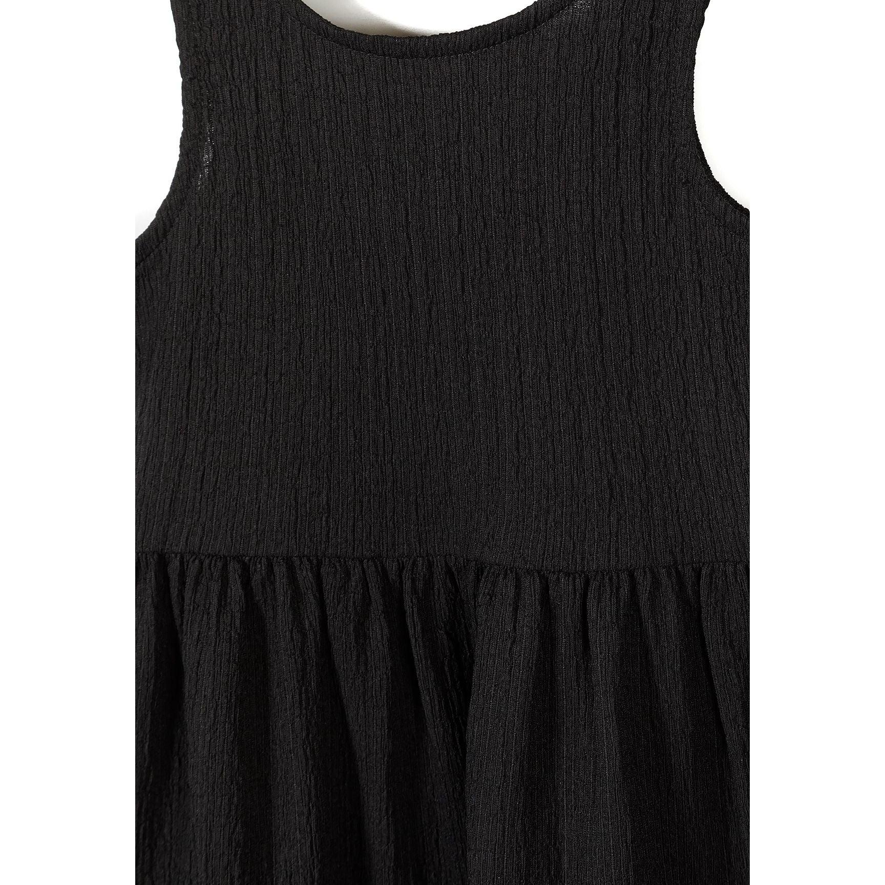 Close-up detail of black ribbed fabric texture and sleeveless bodice construction showing gathered waistline transition