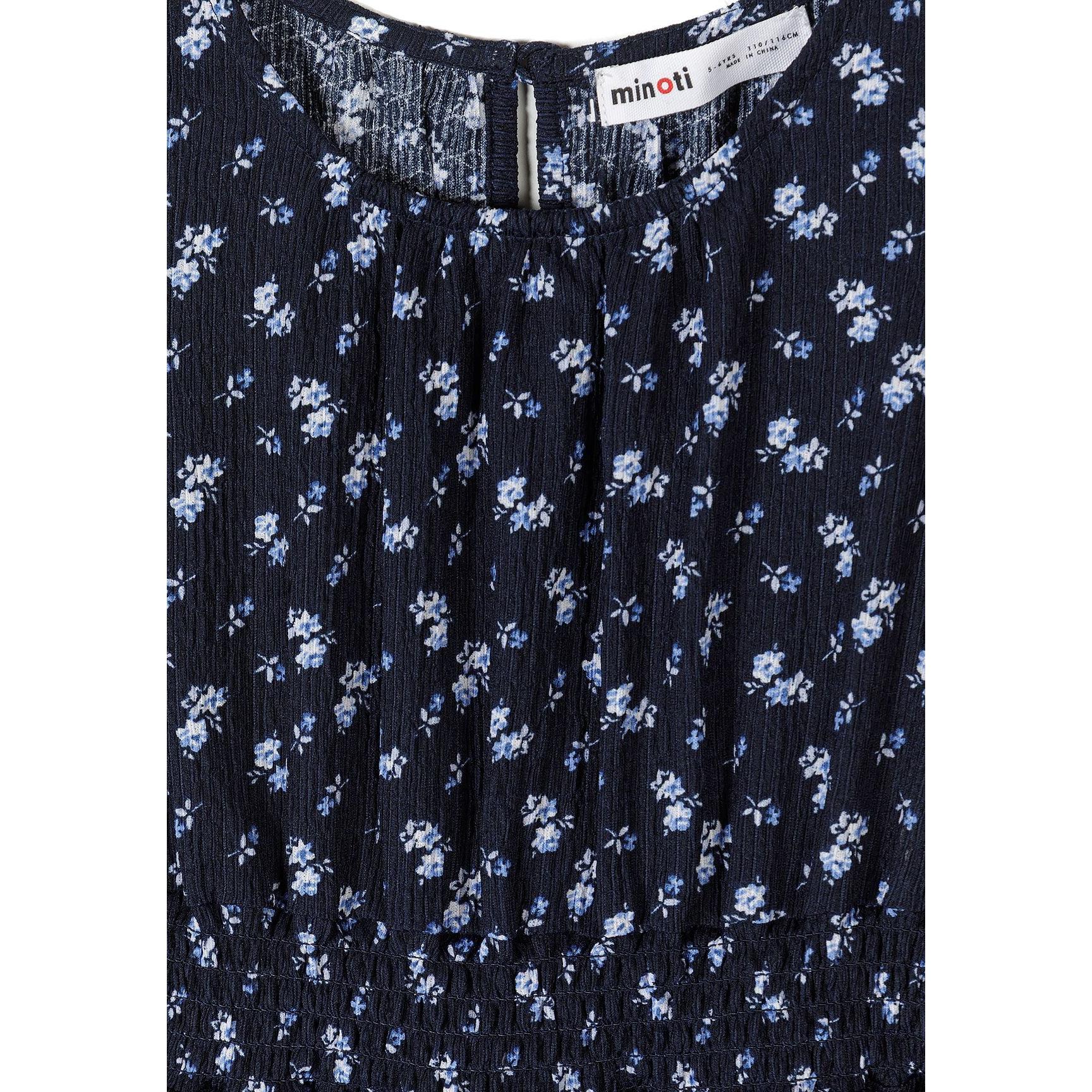 Close-up detail of navy dress neckline showing Minoti label, keyhole button closure, and intricate blue white floral pattern on fabric