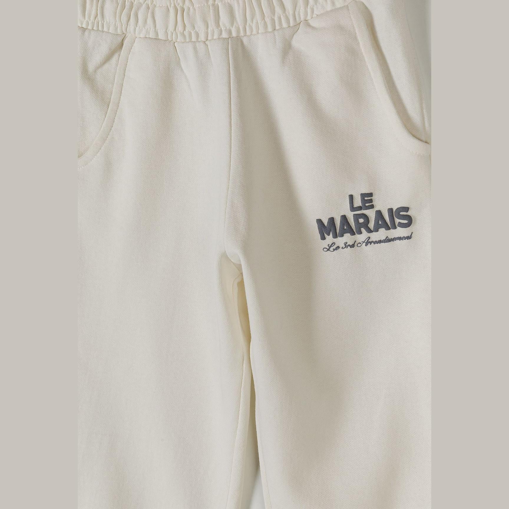 Close-up detail of off white joggers showing elastic waistband and Le Marais text print on leg