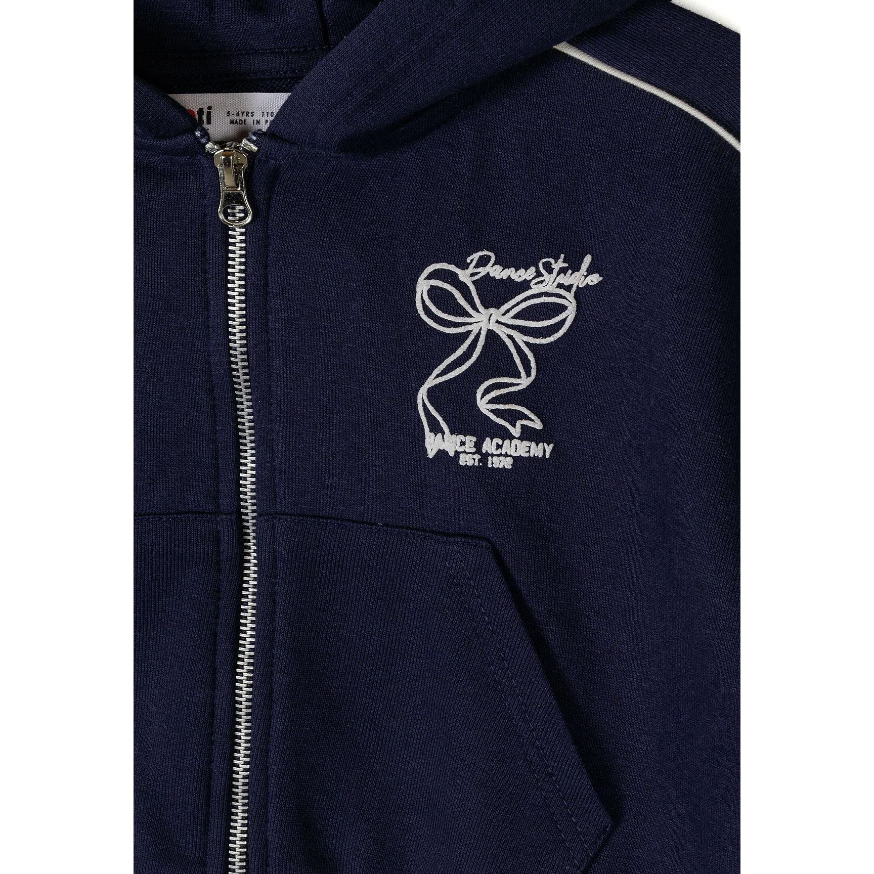 Close-up detail of navy tracksuit jacket showing Dance Studio logo embroidery, silver zip and front kangaroo pocket