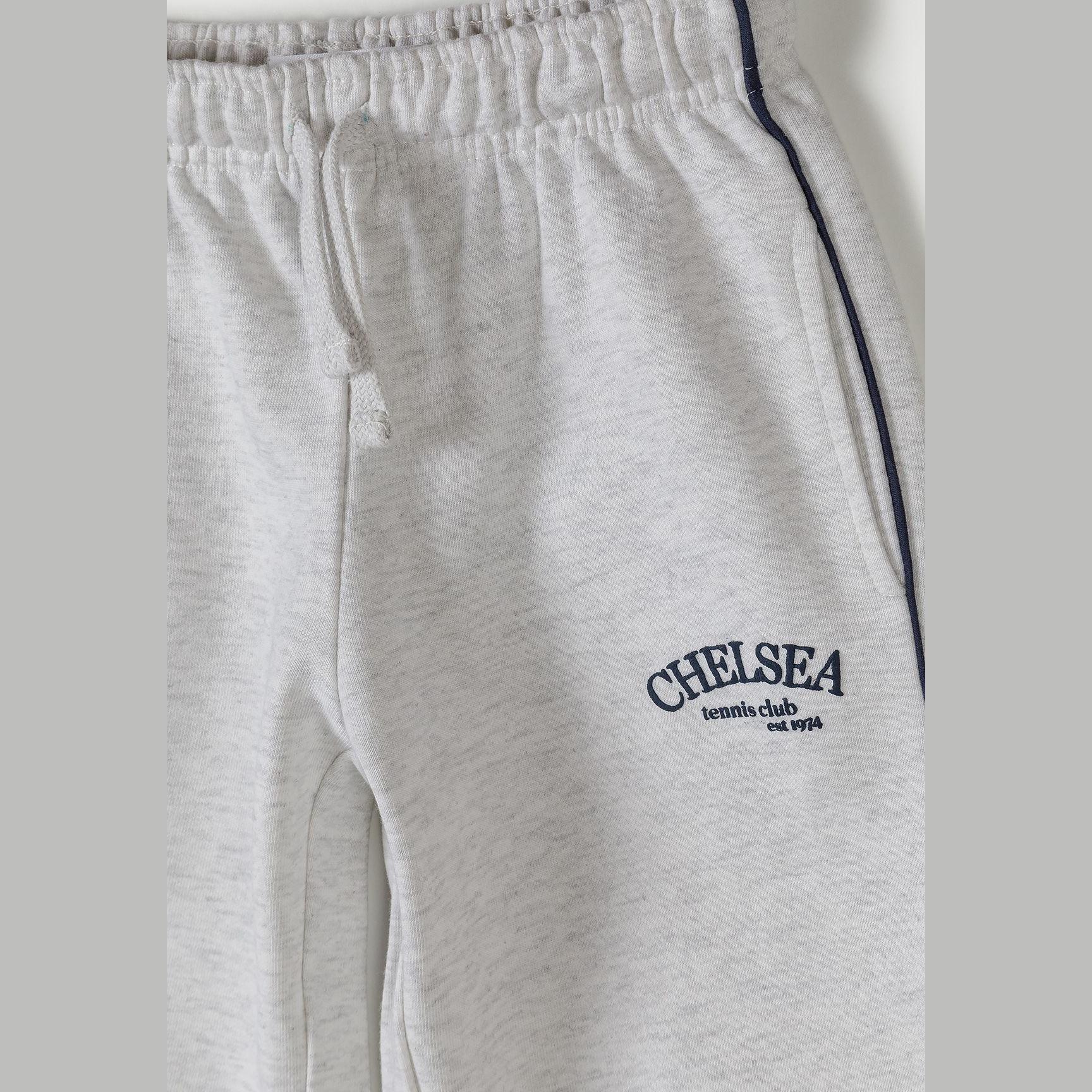 Close-up detail of grey marl joggers showing Chelsea team club est 1924 embroidery and black side piping on white background