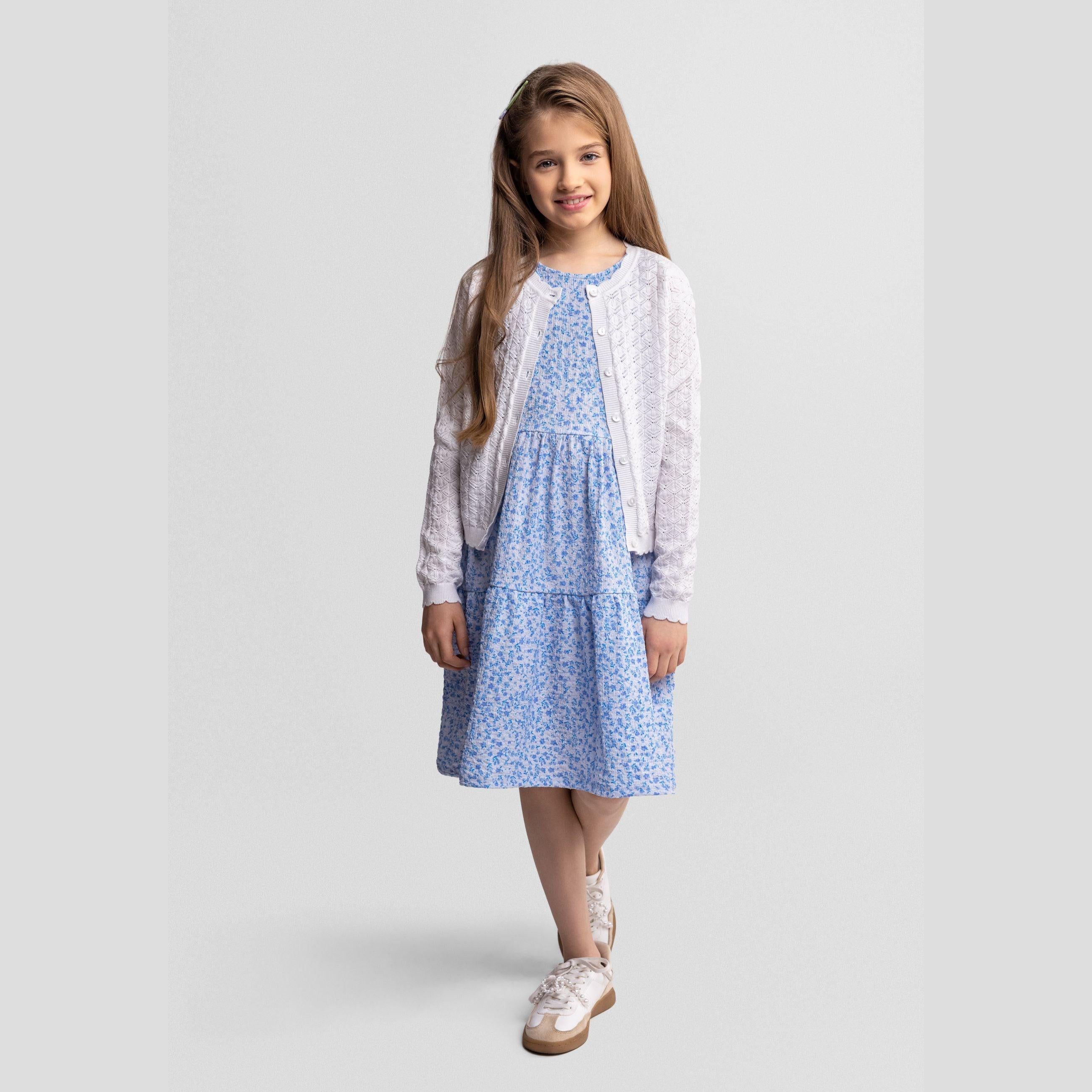 White knitted cardigan laid flat showing button closure and wavy textured pattern detail
