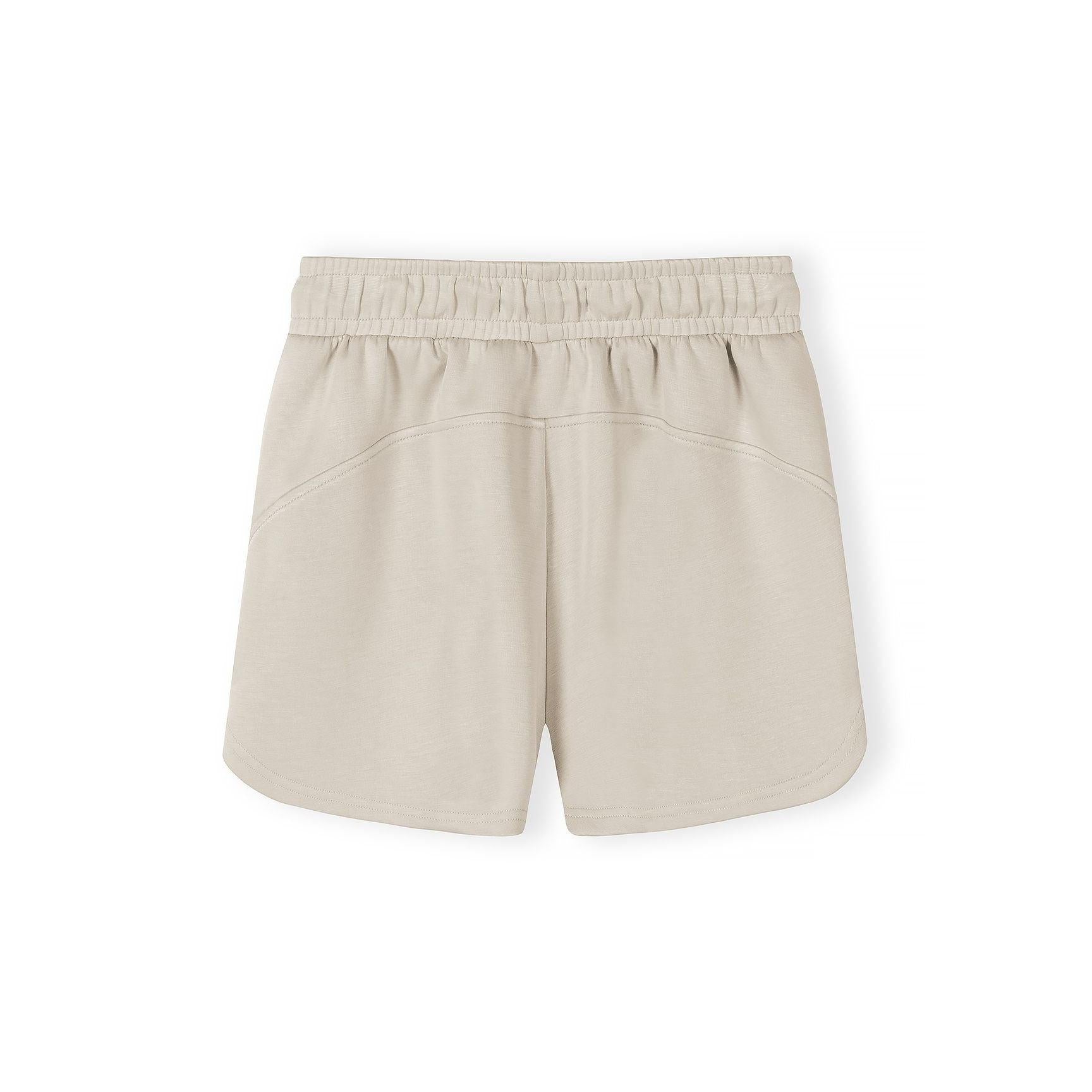 Detail shot of beige shorts waistband and pocket construction with Minoti label visible