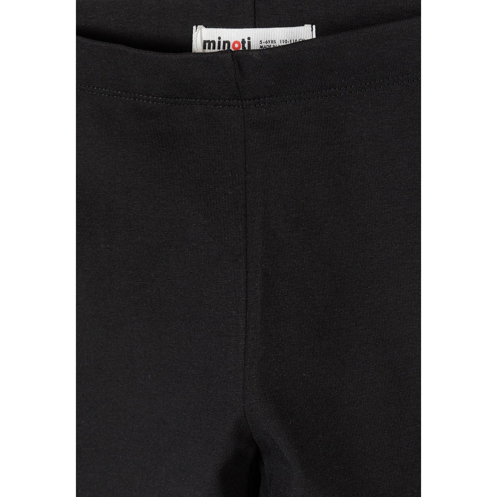 Close-up detail of black cycling shorts showing Minoti brand label at waistband and fabric texture