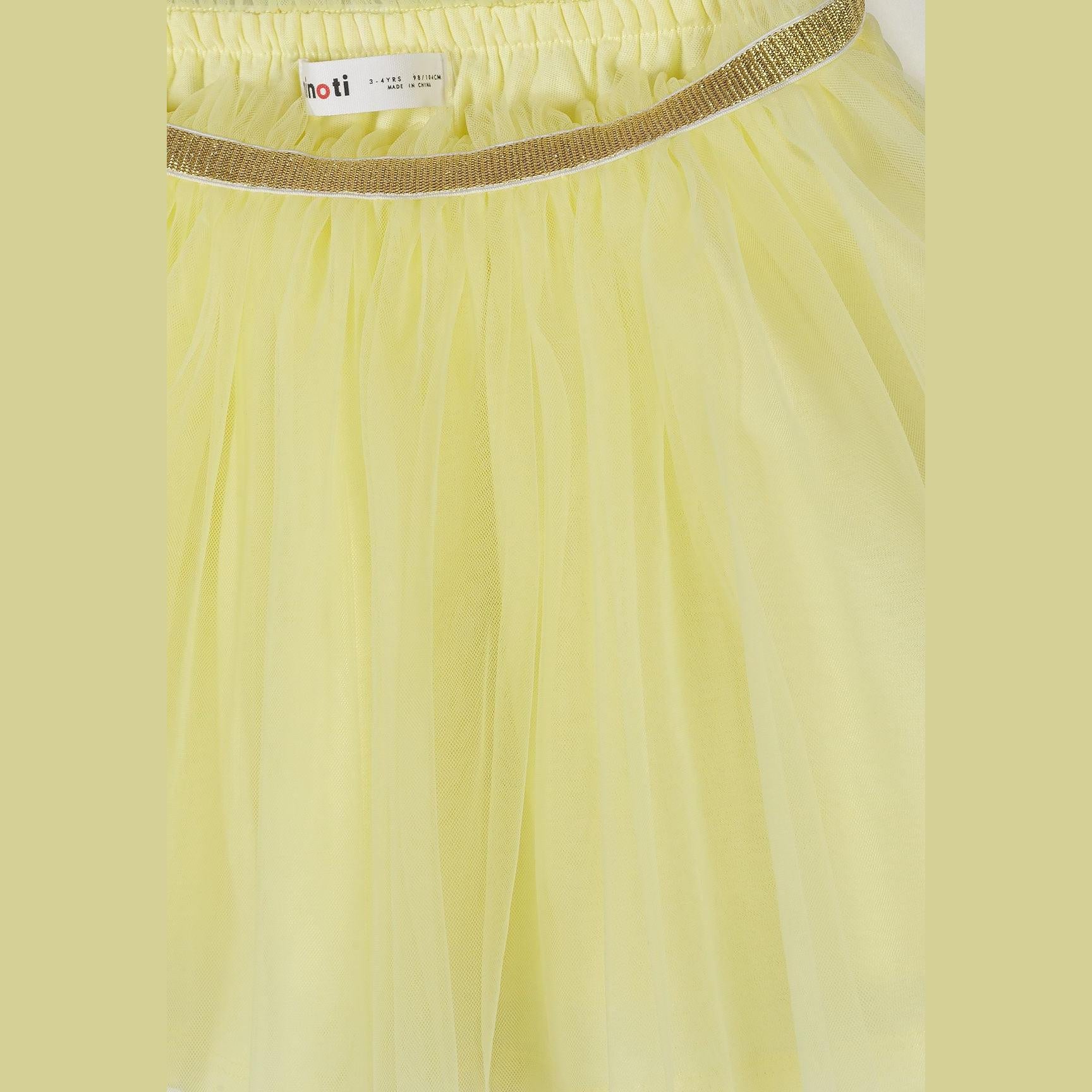 Close-up detail of light yellow tulle skirt waistband showing Minoti label and gold metallic elastic trim with gathered mesh layers
