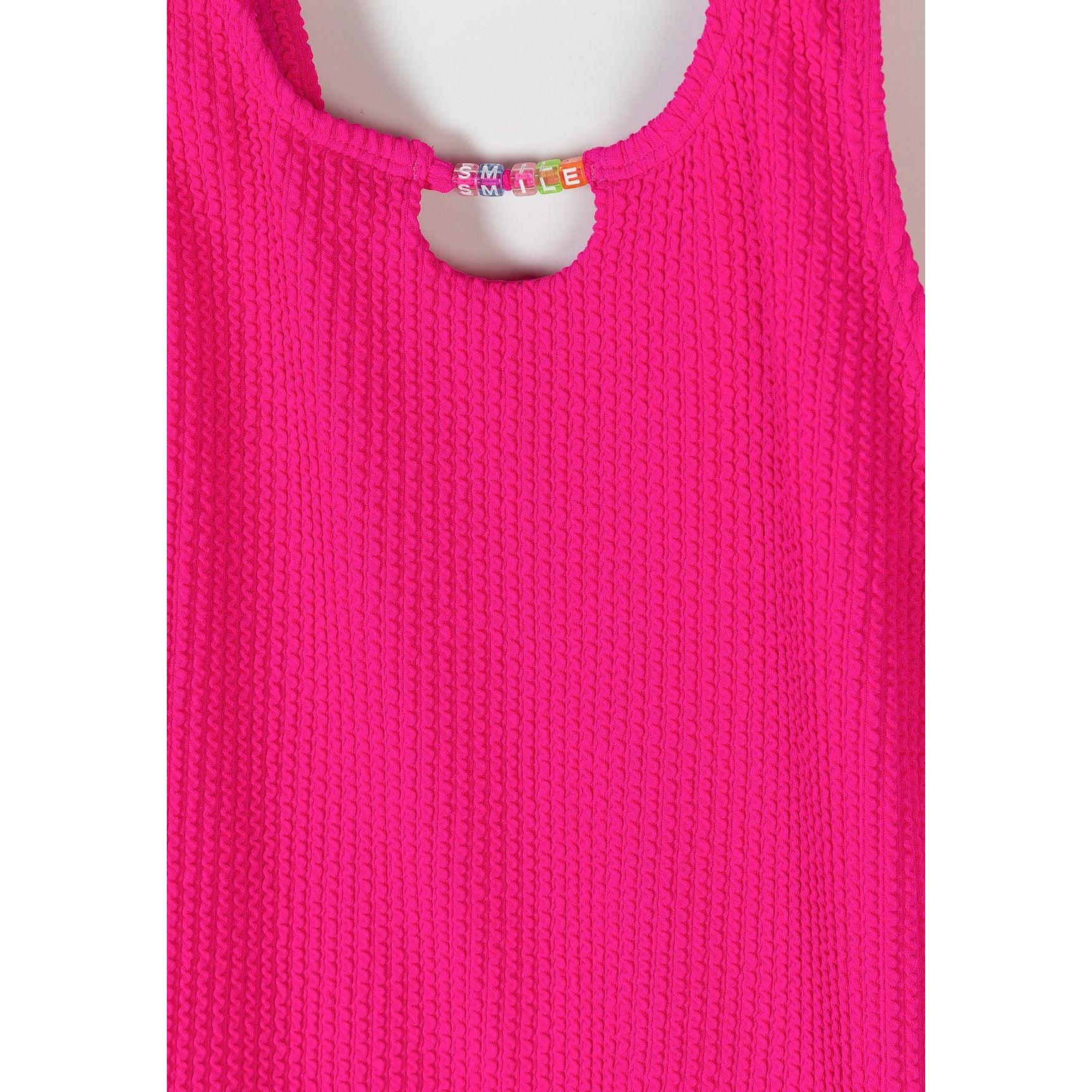 Close-up detail of pink ribbed fabric texture and pearl decorative trim at neckline