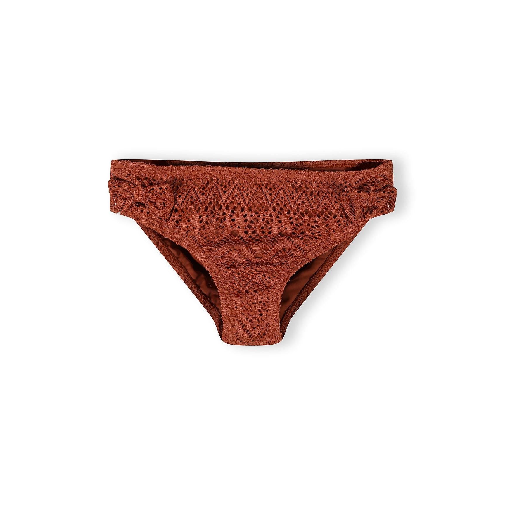 Close-up detail of copper crochet bikini showing intricate diamond and geometric lace pattern with gold charm detail on adjustable strap