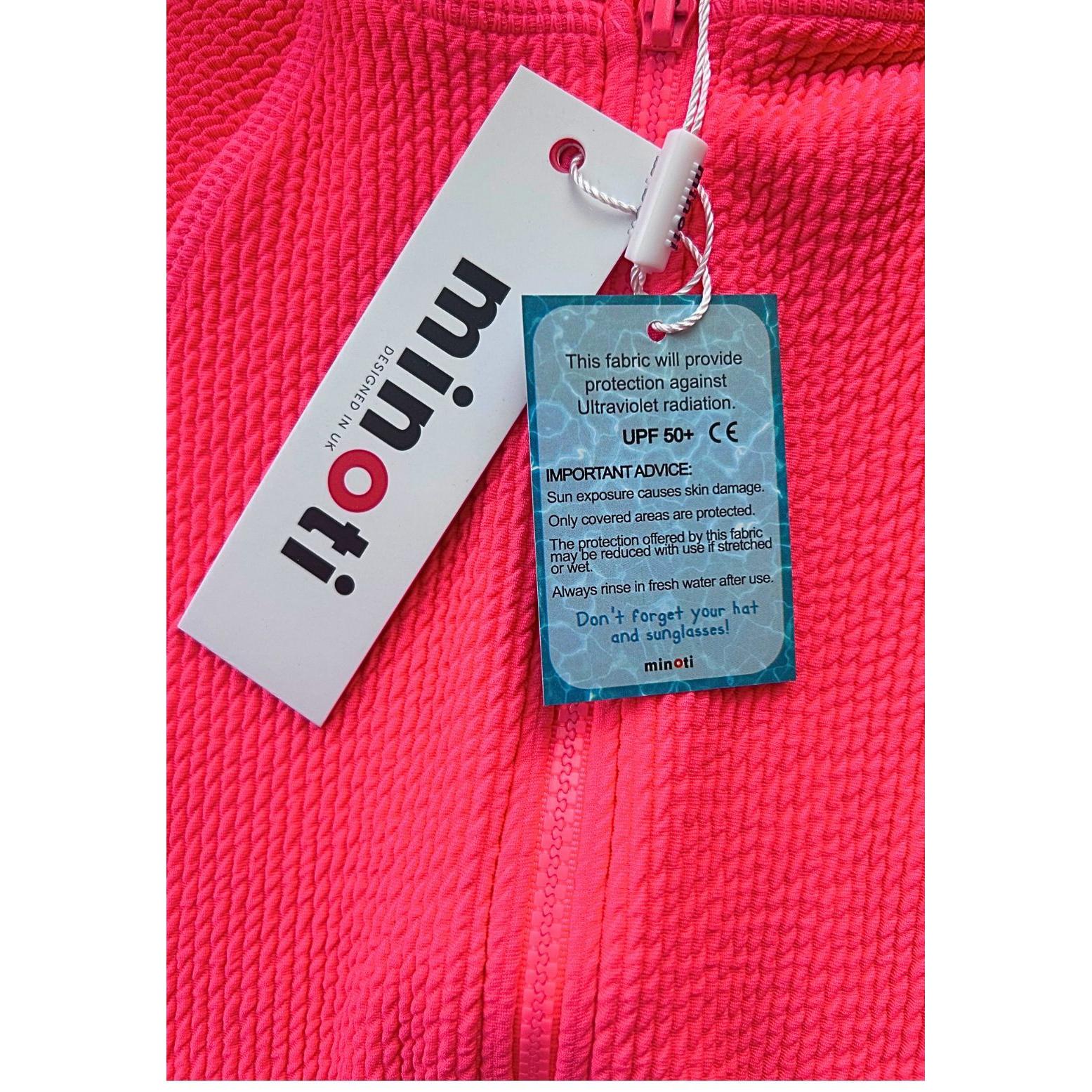 Product tags attached to pink swimsuit showing Minoti brand label and blue UPF 50+ sun protection information tag