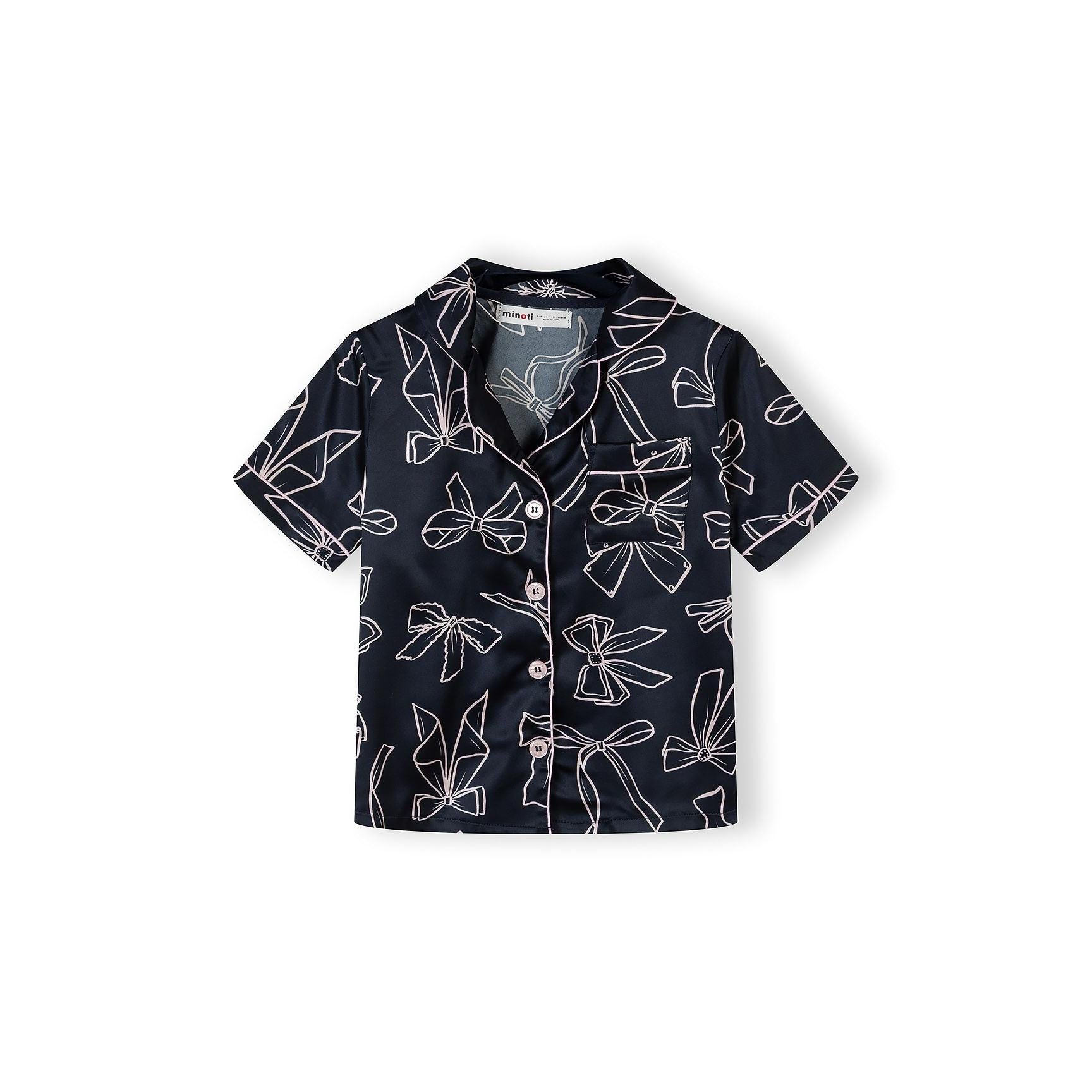 Close-up of navy satin pyjama shorts with white bow print pattern and elasticated waistband, showing Minoti label