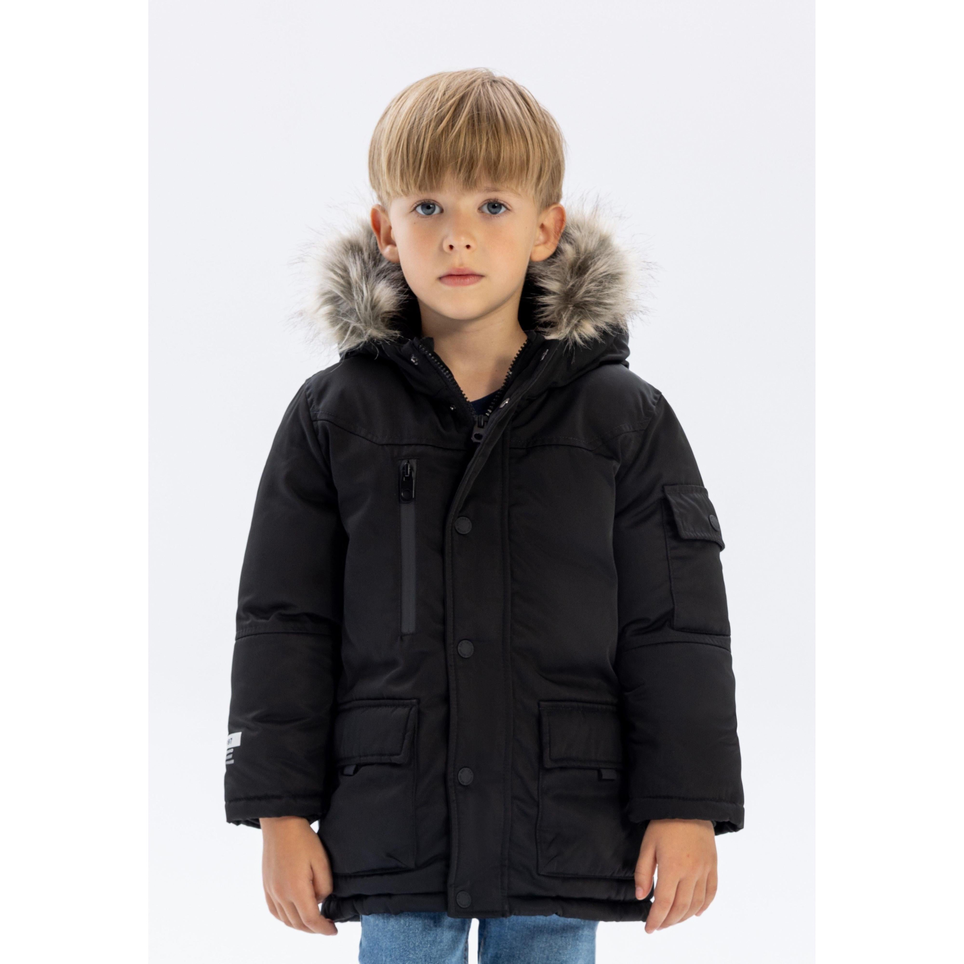 Young boy wearing black long parka with faux fur hood trim, front view against white background