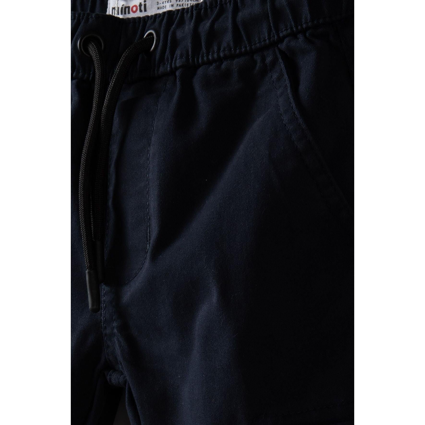 Close-up detail of navy combat trousers waistband showing Minoti label and drawcord ties