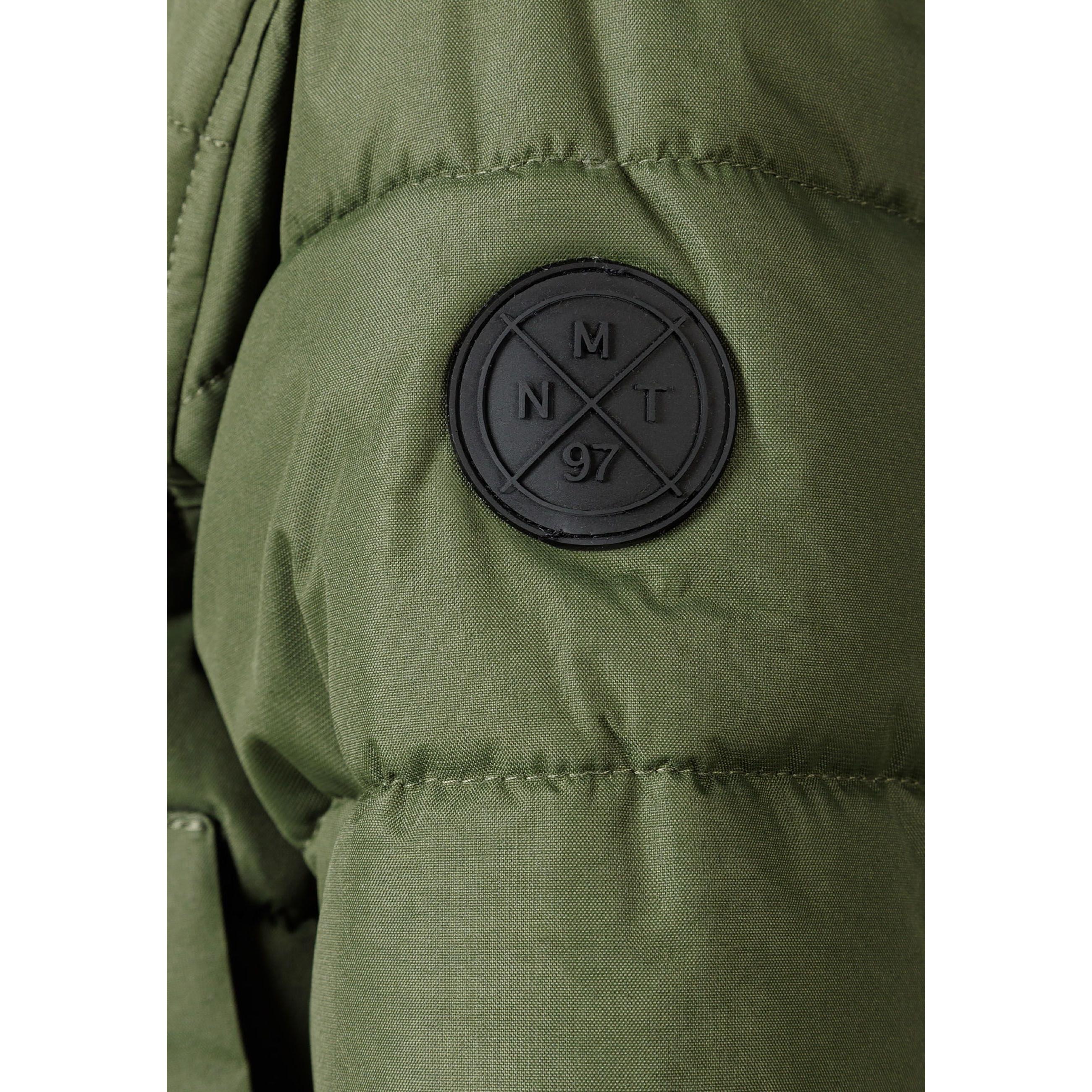 Close-up detail of khaki padded jacket showing circular black Minoti brand badge with crossed design and number 97