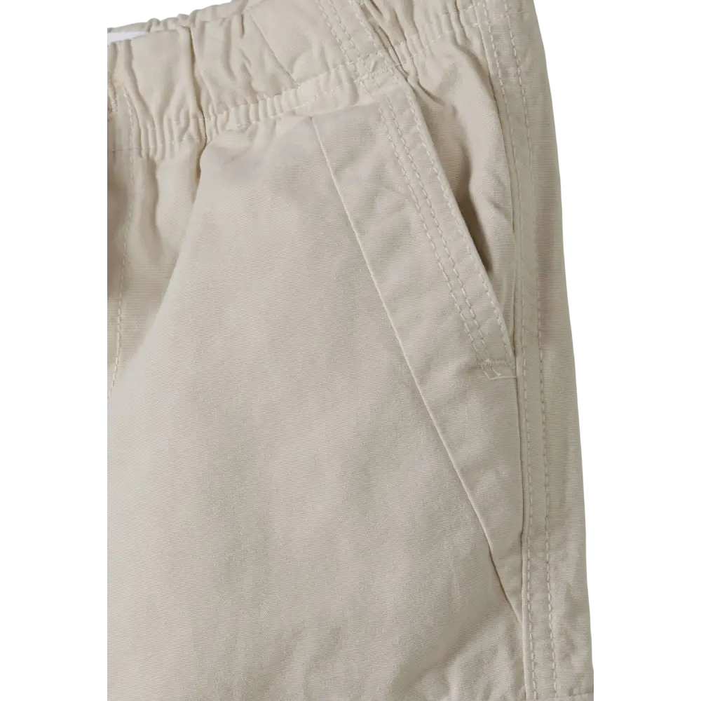 Close-up detail of grey cargo trousers showing side seam construction and fabric texture on black background