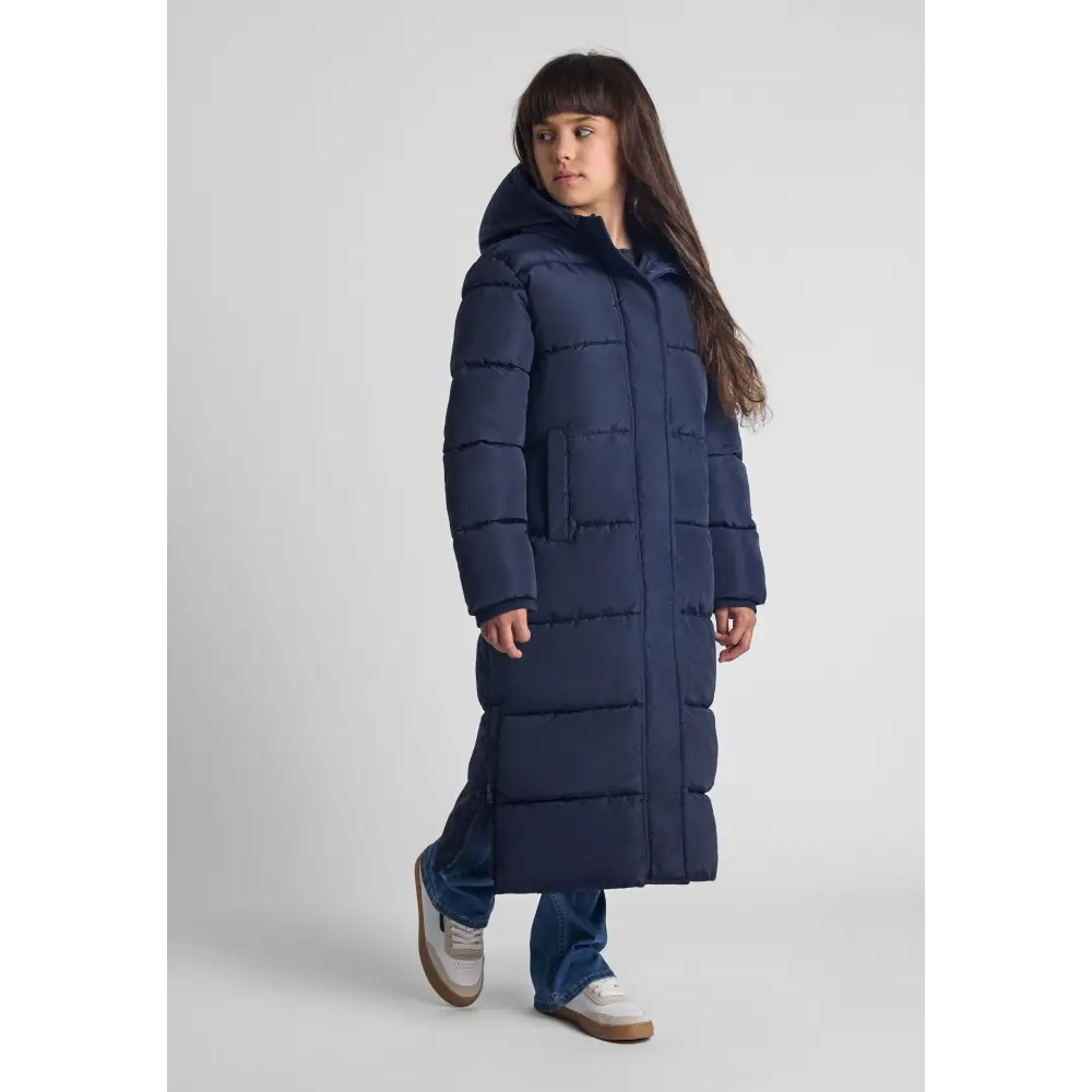 Girl wearing long navy quilted parka with fixed hood, full-length view against light grey background