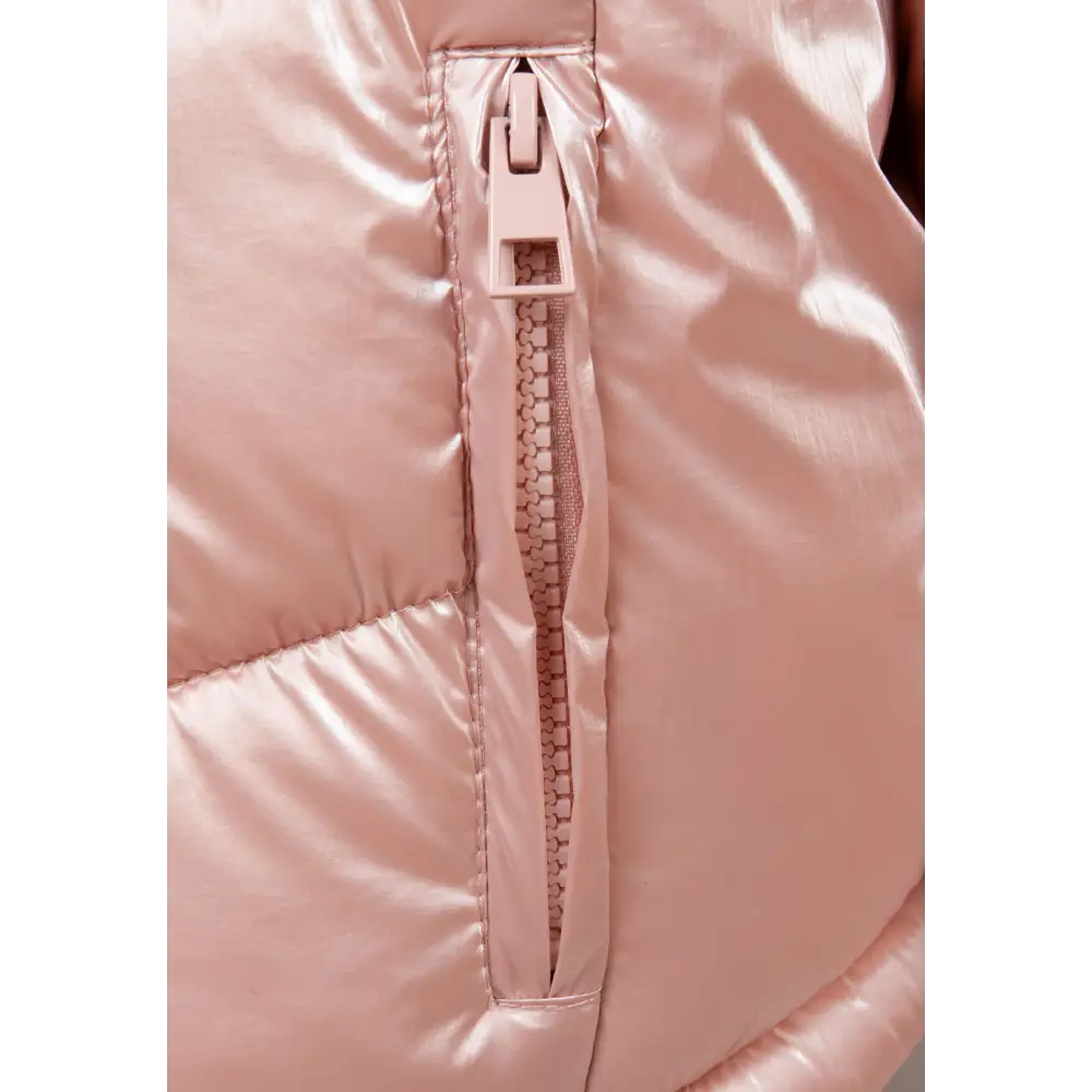 Close-up detail of metallic pink jacket showing zip closure, quilted texture and reflective fabric surface
